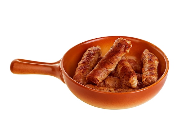 Salchichas envueltas en tocino en una sartén chevapchichi sobre fondo blanco.