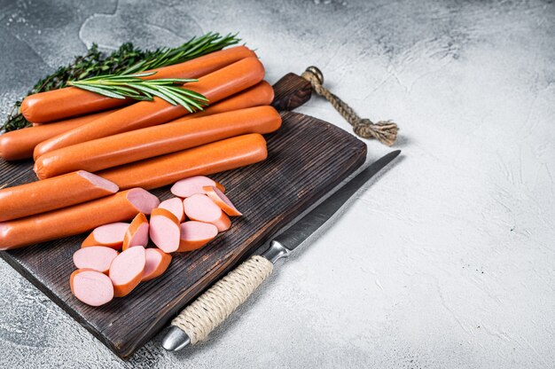 Salchichas Frankfurter cruda alemana sobre una tabla de madera