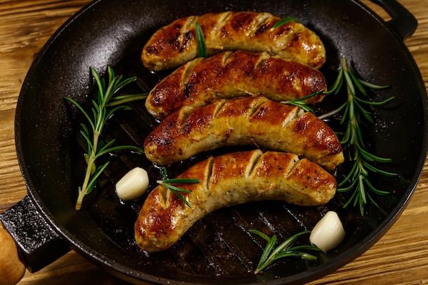 Salchichas fritas con ajo de romero y especias en sartén a la parrilla de hierro fundido