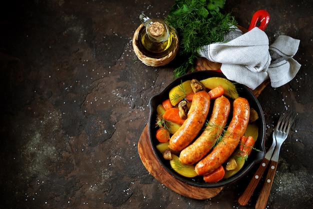 Salchichas fritas con patatas, champiñones y cebollas en una sartén