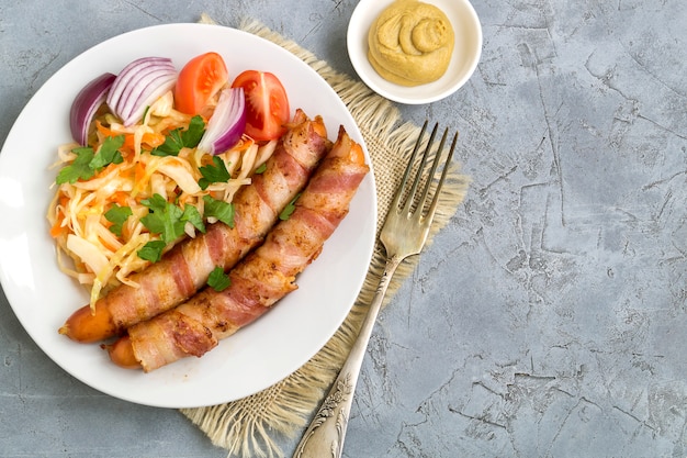 Salchichas fritas con tocino en un plato.