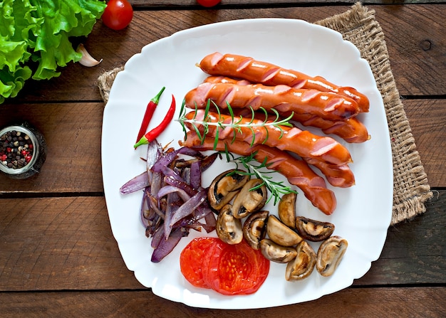 Salchichas fritas con verduras en un plato blanco