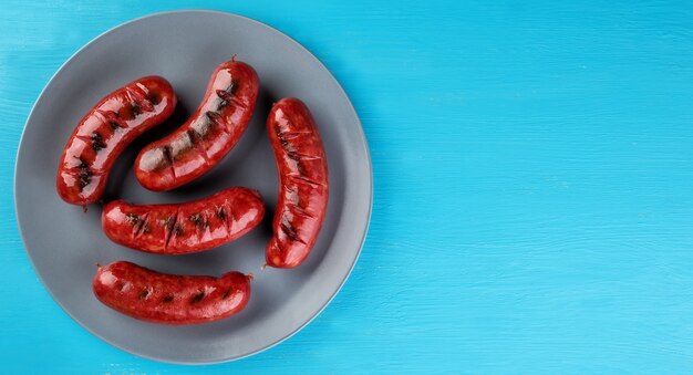 Salchichas jugosas fritas en un plato azul