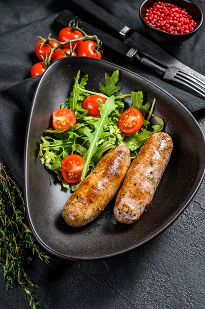 Salchichas a la parrilla con ensalada de tomate y rúcula.