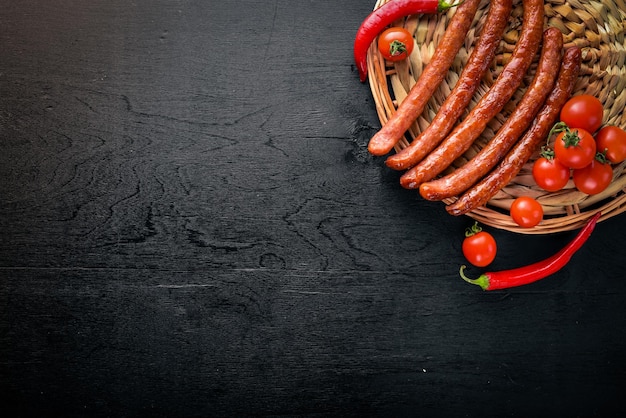 Salchichas a la parrilla en una sartén con verduras frescas De madera en la superficie negra Vista superior