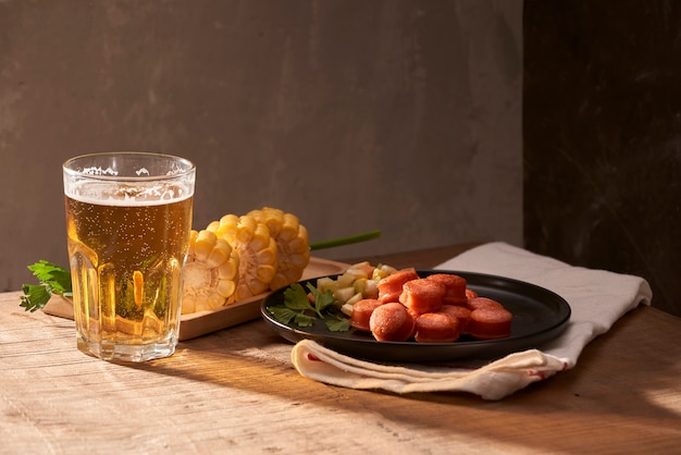 Salchichas a la parrilla con vaso de cerveza en la mesa de madera con espacio de copia.