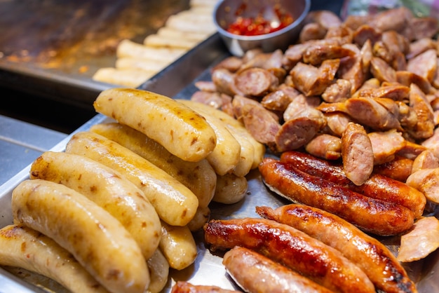 Las salchichas a la parrilla se venden en el mercado callejero por la noche.