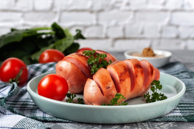 Salchichas a la parrilla con verduras frescas están en el plato.