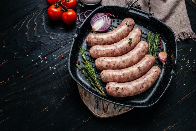 Salchichas rellenas crudas en sartén Salchichas en utensilios de cocina Salchichas para asar menú de banner lugar de recetas para vista superior de texto