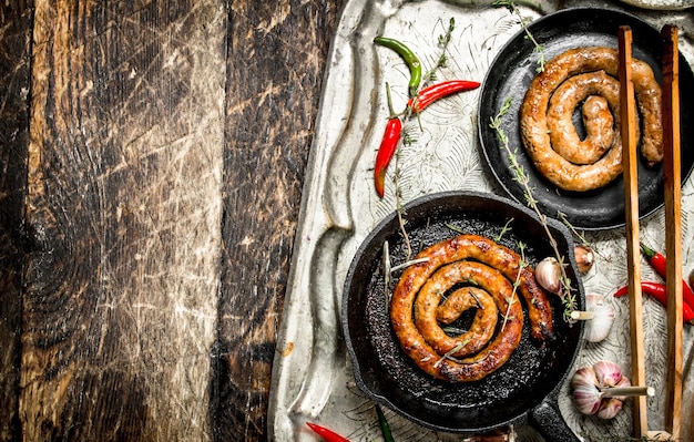 Salchichas en sartenes en una bandeja de acero con pimientos picantes