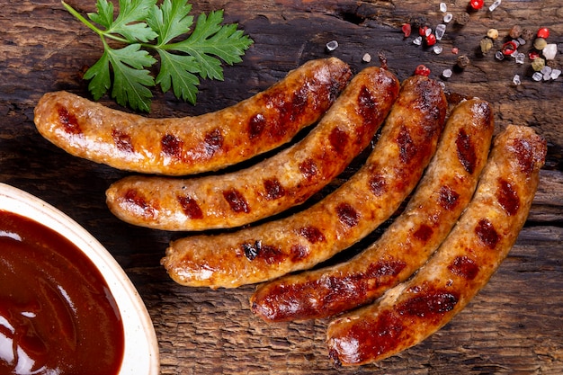 Salchichas de ternera y cerdo picadas a la parrilla con salsa barbacoa sobre tabla de madera