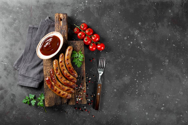 Salchichas de ternera y cerdo picadas a la parrilla con salsa barbacoa sobre tabla de madera