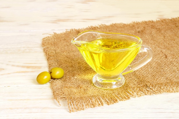 salchichón de vidrio con aceite de oliva virgen extra y aceitunas verdes frescas en tela de burlap en una mesa de madera