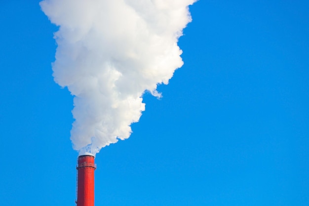 Sale humo de una chimenea roja contra un cielo azul