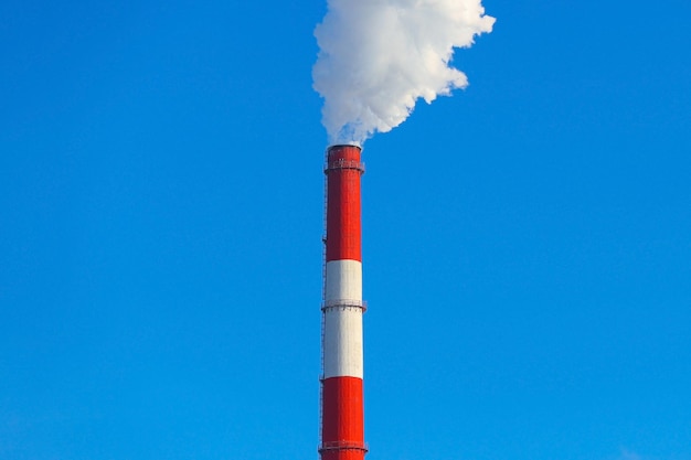 Sale humo de una chimenea roja contra un cielo azul