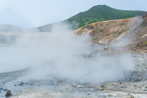 Salida hidrotermal humeante en la orilla del lago caliente en la caldera del volcán Golovnin en la isla de Kunashir