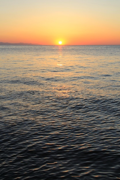 Salida del sol en el mar. Cielo naranja. Ondas.