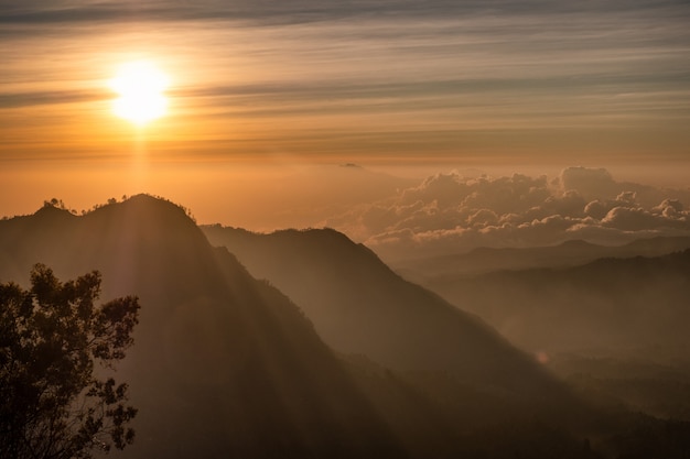 Salida del sol sobre la montaña con niebla con pueblo en colina