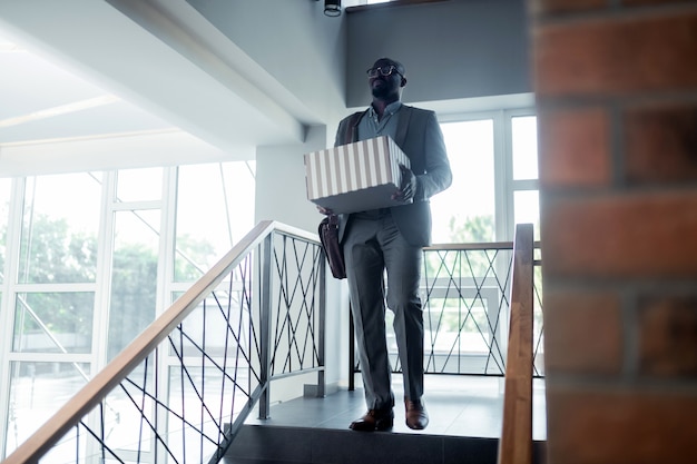 Foto saliendo de la oficina. trabajador de oficina vistiendo traje saliendo de la oficina con su caja después de ser despedido