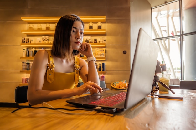 Foto salientou a mulher usando o computador portátil no café