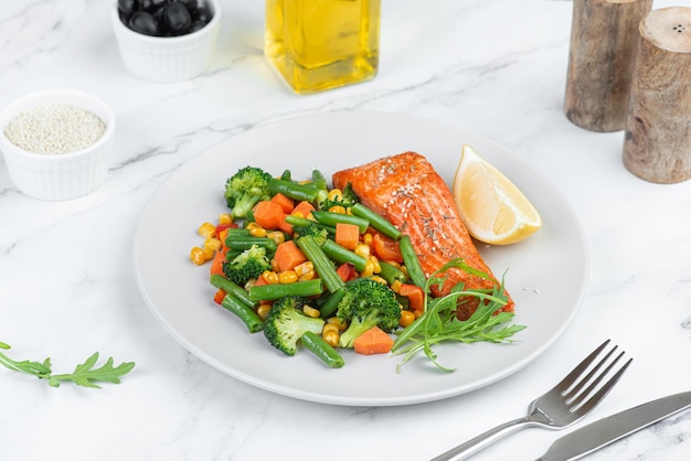 Salmão assado com legumes em um fundo cinza