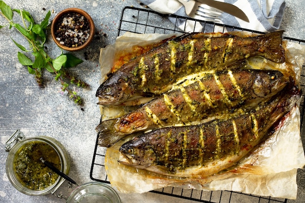 Salmão assado com molho pesto e temperos culinários em uma bancada de pedra cinza Vista superior