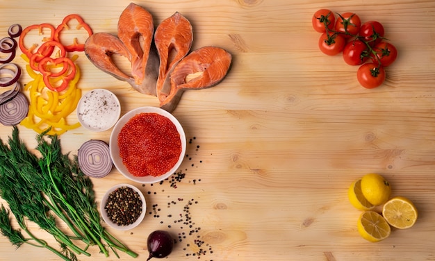 Salmão. bifes de truta em mesa de madeira natural decorada com um prato com caviar vermelho, legumes e ervas. conceito de comida saudável. lugar para inscrição