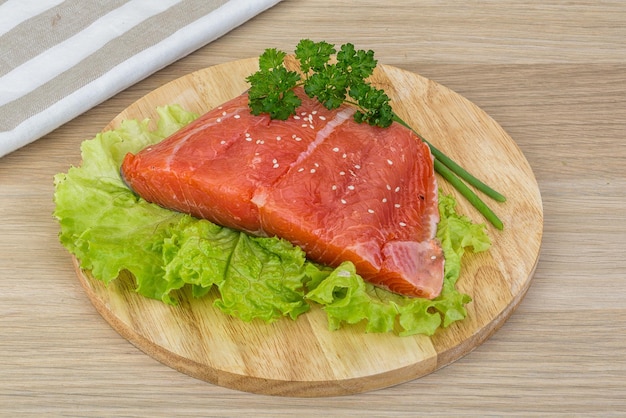 Foto salmão com salada de folhas e salsa em fundo de madeira