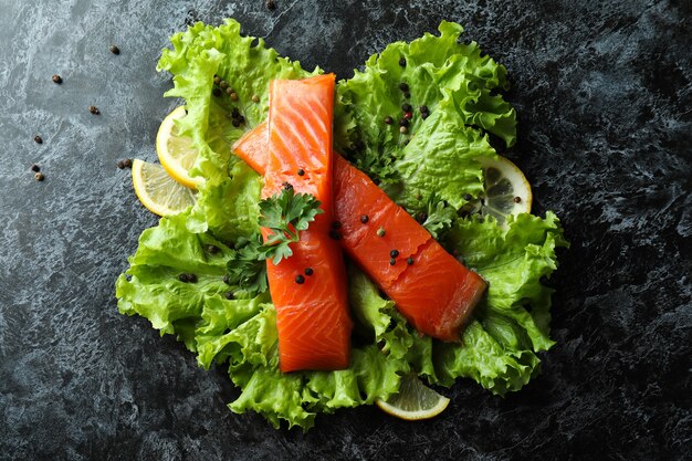 Salmão cru fresco e ingredientes para cozinhar em fundo preto esfumaçado