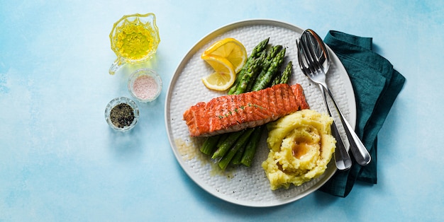 salmão grelhado com aspargos frescos e purê de batatas em um prato. comida saudável em cima da mesa