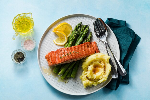 salmão grelhado com aspargos frescos e purê de batatas em um prato. comida saudável em cima da mesa