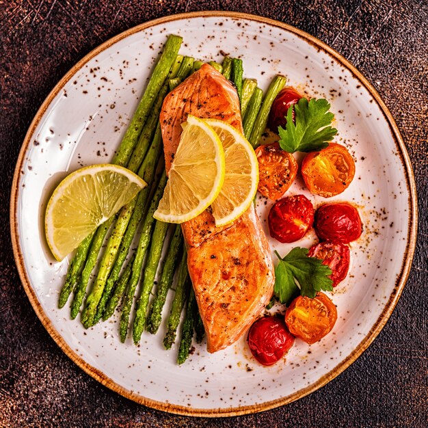 Salmão grelhado com espargos e tomates, vista superior.