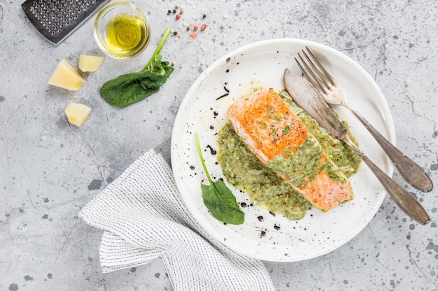 Salmão grelhado com espinafre e molho de creme de alho em um prato, vista de cima