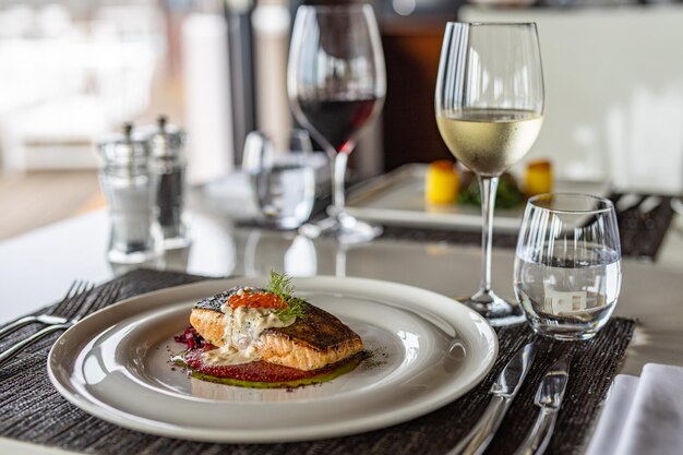 Salmão grelhado com molho de legumes servido na mesa elegante de chapa branca. Comida de luxo gourmet, vinho