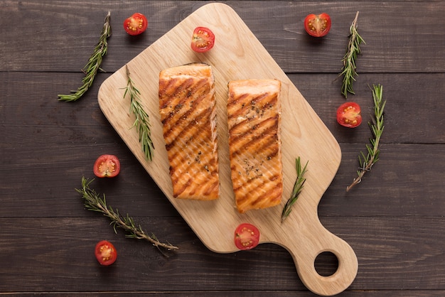 Salmão grelhado e tomate, alecrim na mesa de madeira