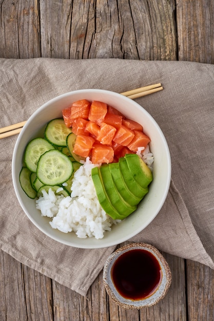 Foto salmão pique tigela com peixe fresco, arroz, pepino, abacate com gergelim preto e branco.