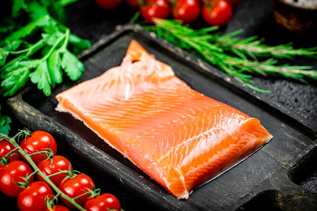 Salmão salgado com verduras e tomates em uma tábua de cortar