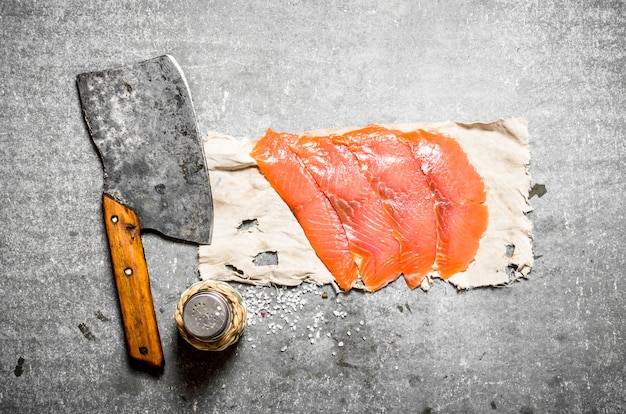 Salmón ahumado en rodajas finas con hacha y sal.