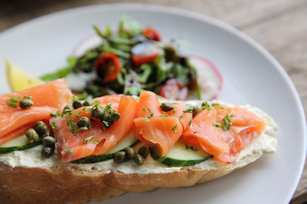 salmón ahumado sobre pan tostado con crema fresca, limón y ensalada