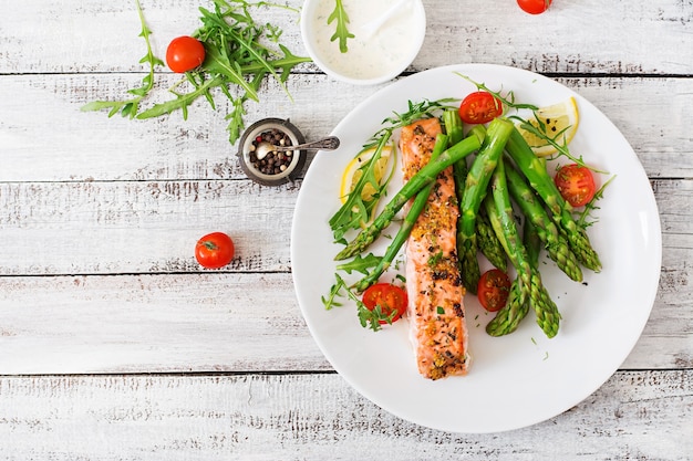 Salmón al horno adornado con espárragos y tomates con hierbas