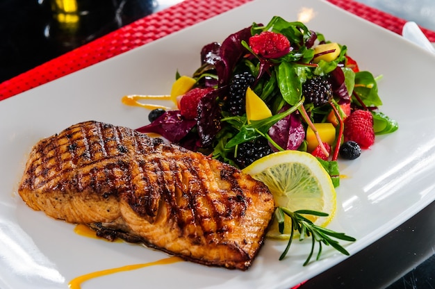 Salmón asado con guarnición de frutos rojos.