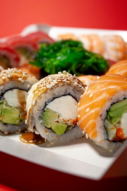 salmón atún chuka camarones anguila nigiri gunkan rollos de sushi en una caja blanca sobre fondo rojo