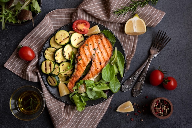 Salmón cocido con verduras sobre fondo oscuro