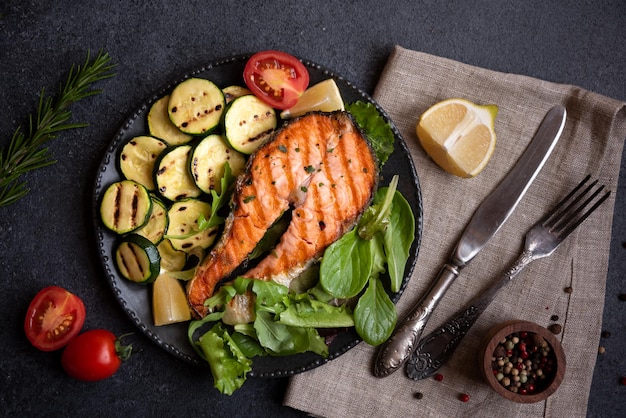 Salmón cocido con verduras sobre fondo oscuro