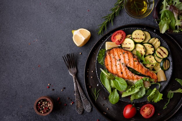 Salmón cocido con verduras sobre fondo oscuro