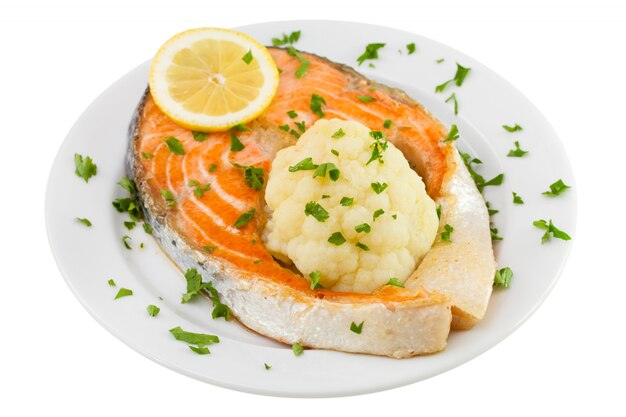 Salmón con coliflor en el plato sobre fondo blanco