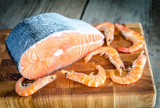 Salmón crudo y camarones en la tabla de madera