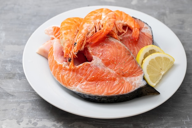 Salmón crudo con limón en un plato blanco sobre mesa de cerámica