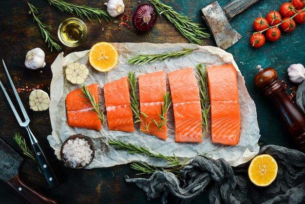 Salmón crudo con romero, limón y verduras sobre un fondo de piedra negra Mariscos Vista superior Espacio libre para texto