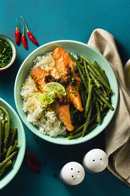 salmón fresco frito con jengibre y ajo en leche de coco, con arroz basmati y judías verdes en platos sobre la mesa. receta saludable para toda la familia.